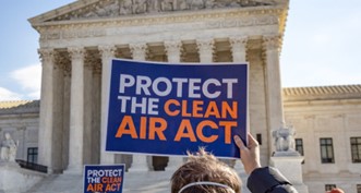 Protester outside the Supreme Court holds up a sign reading "Protect the Clean Air Act."
